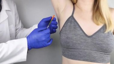 Klinikte hiperhidrozun tedavisi için koltukaltına botulinyum toksin enjekte edilen bir kadın. Artan terleme, anhidroz ya da arızalı bezlerle ilgili sorunların tedavisi. Kozmetoloji