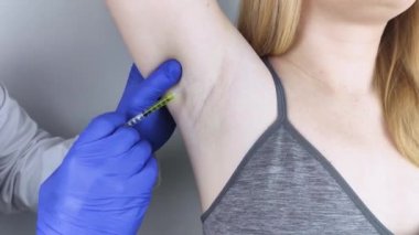 Klinikte hiperhidrozun tedavisi için koltukaltına botulinyum toksin enjekte edilen bir kadın. Artan terleme, anhidroz ya da arızalı bezlerle ilgili sorunların tedavisi. Kozmetoloji