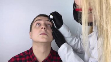 Göz damlasına yakın çekim. Doktor randevusunda, hastanın gözlerine damlayan bir adam. Konjonktivit tedavisi, göz yorgunluğu, glokom. Viral veya bakteriyel enfeksiyonlar