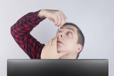 Göz damlasına yakın çekim. Yapay yırtık. Gözlerinde ağrı var. Gözlerde metanet hissi. Bir adam bilgisayar monitörü ya da dizüstü bilgisayarın arkasından dışarı bakar. Kendi göz ilacımı akıtacağım.