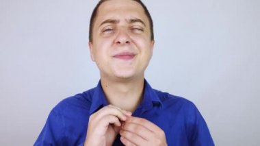 Mavi gömlekli bir ofis çalışanı kameraya bakar. Ter lekesiyle kaplıydı. Adamın çok fazla stresi var ve yanında terlemesi de var. İş adamı gergin ve çok terliyor..