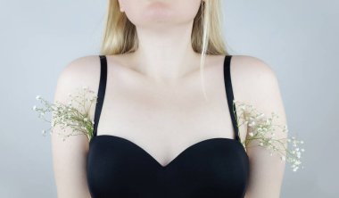 Bir kadının koltukaltında büyüyen saçları simgeleyen çiçekler vardır. Kavramsal fotoğraf. Vücut pozitifliği ve vücut kabulü. Tıraş bıçağı ya da lazerle saç kesimi. Kişisel bakım.