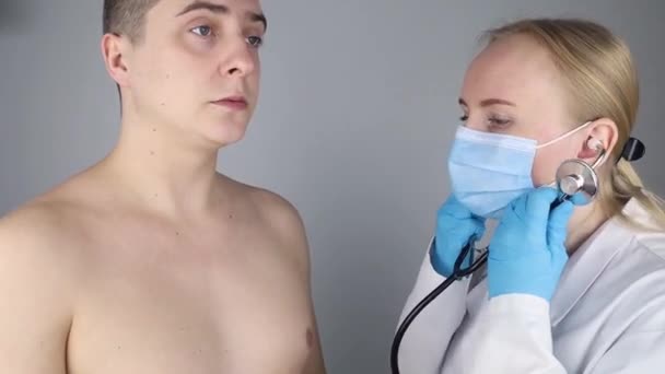 競売にかけられた セラピストは患者の肺に耳を傾ける 男は咳と呼吸困難を訴えている ガウン マスク フォノ内視鏡を着た医者が患者を検査する — ストック動画