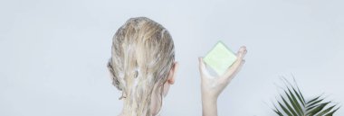 Saf saç şampuanı. Saçını kuru şampuanla yıkayan sarışın bir kızın banyodaki yakın çekimi. Bol köpüklü ve dikiz efektli..