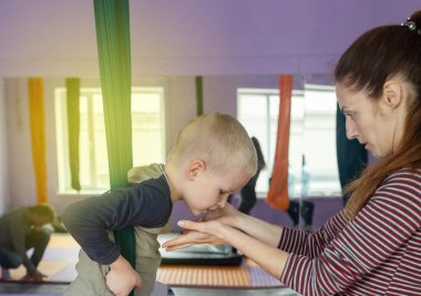 Çocuklar için sinek yogası. Çocuklar ve koç bez tuvaller üzerinde hava akrobasisi yapıyorlar. Ebeveynler ve çocuklar hamaklarda eğitim görüyorlar. Hava jimnastiği.