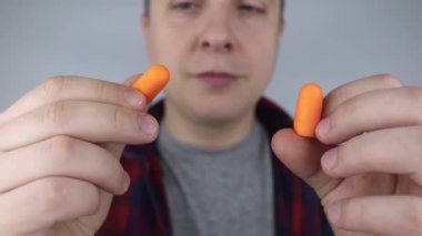 Adam kulak tıkacı takıyor. Turuncu gürültü bariyerine yakın çekim. Derin uykuda. KBB doktoru çevredeki gürültüyü azaltmak için turuncu kulaklık tavsiye ediyor. Seslere karşı hassasiyet artışı.