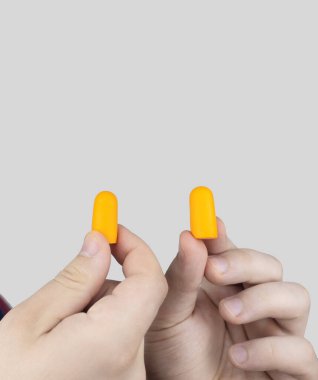 Adam kulak tıkacı takıyor. Turuncu gürültü bariyerine yakın çekim. Derin uykuda. KBB doktoru çevredeki gürültüyü azaltmak için turuncu kulaklık tavsiye ediyor. Seslere karşı hassasiyet artışı.