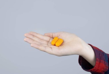 Adam kulak tıkacı takıyor. Turuncu gürültü bariyerine yakın çekim. Derin uykuda. KBB doktoru çevredeki gürültüyü azaltmak için turuncu kulaklık tavsiye ediyor. Seslere karşı hassasiyet artışı.