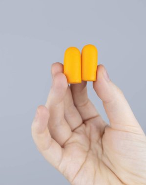 Adam kulak tıkacı takıyor. Turuncu gürültü bariyerine yakın çekim. Derin uykuda. KBB doktoru çevredeki gürültüyü azaltmak için turuncu kulaklık tavsiye ediyor. Seslere karşı hassasiyet artışı.