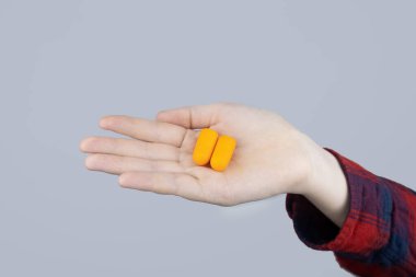 Adam kulak tıkacı takıyor. Turuncu gürültü bariyerine yakın çekim. Derin uykuda. KBB doktoru çevredeki gürültüyü azaltmak için turuncu kulaklık tavsiye ediyor. Seslere karşı hassasiyet artışı.