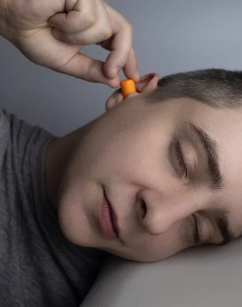 あの男は耳栓をしている オレンジのノイズバリアのクローズアップ 深い眠りだ 耳鼻咽喉科医は 周囲の騒音を減らすためにオレンジの耳痛をお勧めします 音に対する感度の向上 — ストック写真