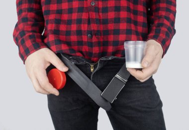 Man takes semen analysis. Spermogram. Concept. Male with his pants unbuttoned symbolizes preparation for analysis of seed for infertility, sperm motility. Suitability test for artificial insemination