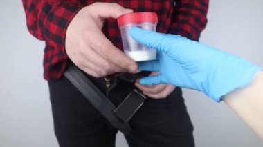 Man takes semen analysis. Spermogram. Concept. Male with his pants unbuttoned symbolizes preparation for analysis of seed for infertility, sperm motility. Suitability test for artificial insemination