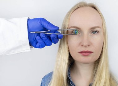 Göz kristal lens değişiminin kavramsal görüntüsü. Ototimik cerrahi. Görüş alanına geri dön. Kataraktların çıkarılması. Gözüne cerrahi müdahale. Doktor implantı hastanın yanında tutuyor.