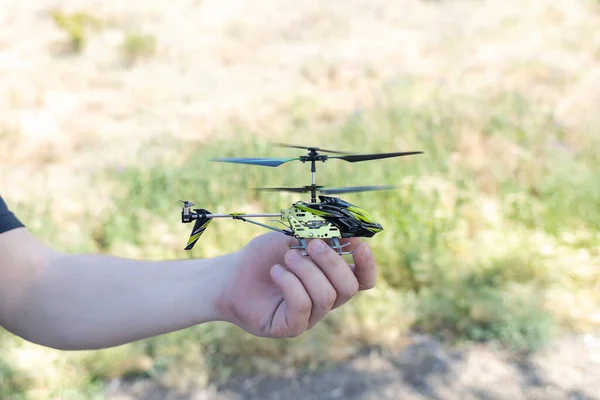 Child and a radio-controlled helicopter. Blond boy holds in his hand a mini model of a helicopter, in which the propellers work. Kid develop fine motor skills. Happy childhood and love of flying