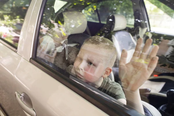 子供は車に閉じ込められた 金髪の少年は水なしで自動車で閉じられます 彼は熱く 顔は赤くなっている 無責任な両親は子供を熱い車の中に置き去りにした 子供のための貧しいケアの概念 — ストック写真