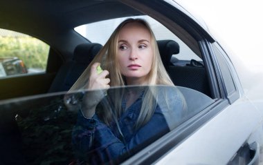 Dry shampoo. Blonde girl sprays shampoo on her hair. The problem of oily hair while traveling. An emergency remedy for excessive sebum production. Make your head clean without water