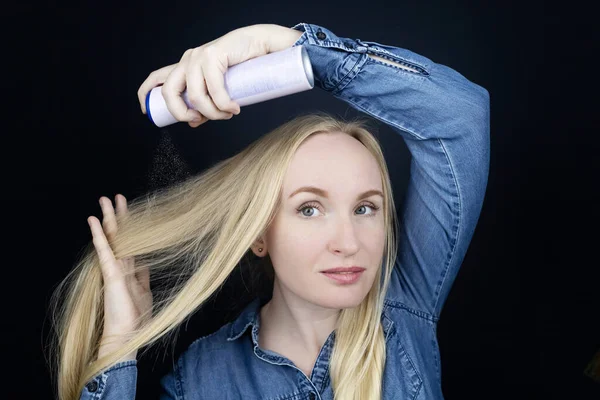 Dry shampoo. Blonde girl sprays shampoo on her hair. The problem of oily hair while traveling. An emergency remedy for excessive sebum production. Make your head clean without water