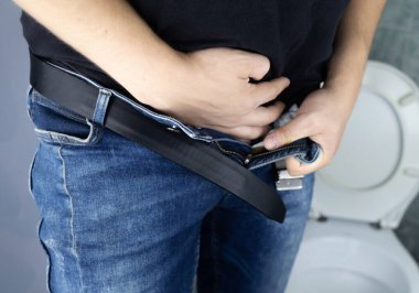 Fahişe konsepti. Bir adamın arka görünüşü, işemesi zor. Prostat iltihabı yüzünden idrar zorluğu çekiyor. Tuvalet manzarası ve bir adamın bacakları. Temiz suyla idrarın taklidi. Tuvalette hasta.