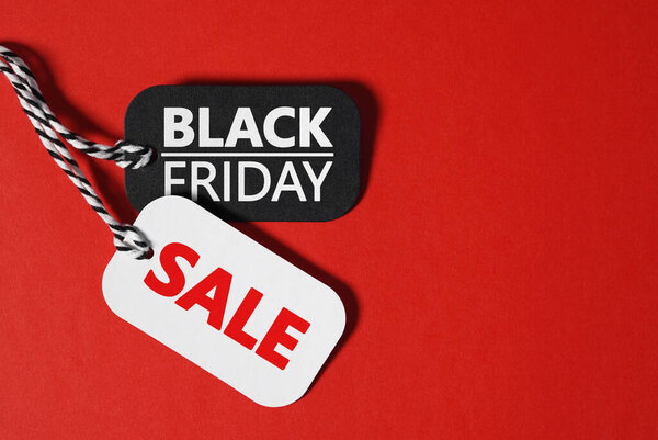 Black friday sale thanksgiving day and Christmas shopping concept with black friday and sale text on black and white paper price tags on red background banner with copy space.