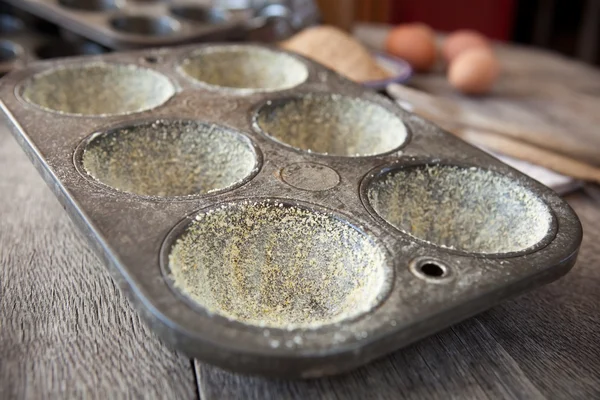 Buttered muffin tin with corn flour — Stock Photo, Image