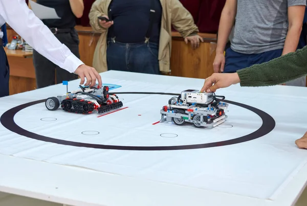 Robotics competitions. Kid's hands and a robot on wheels