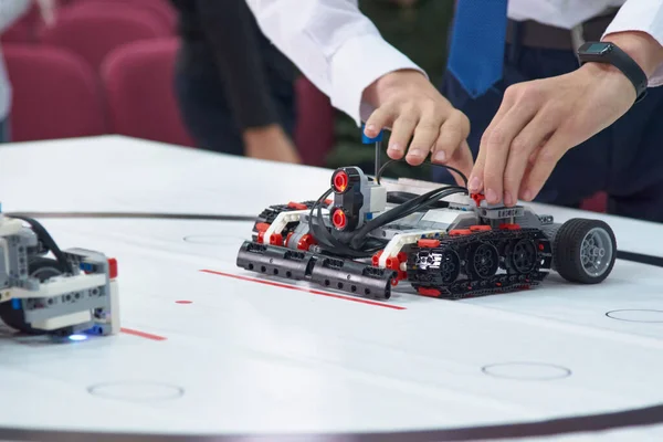Robotics competitions. Kid's hands and a robot on wheels