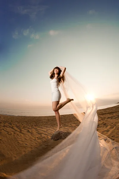 Bella sposa con un lungo velo sulla spiaggia al tramonto — Foto Stock