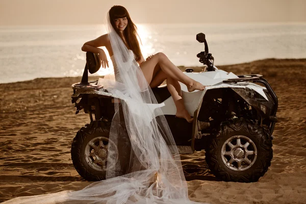 Bride sitting on a quad bike on the beach Stock Photo