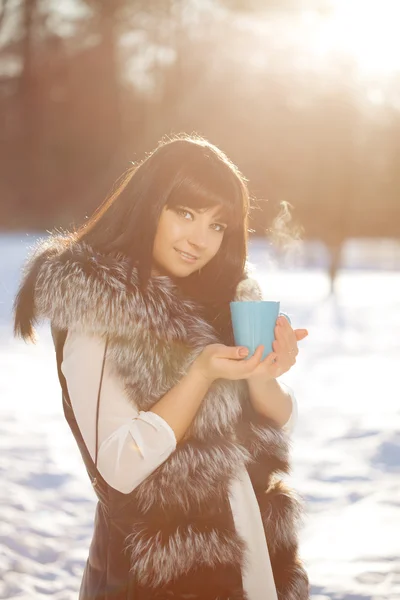 Jeune femme avec une tasse de boisson chaude — Photo