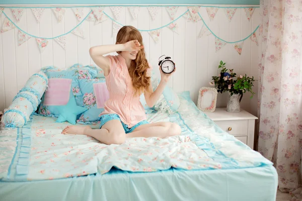 Cute young girl in nice children's bedroom with alarm clock — Stock Photo, Image