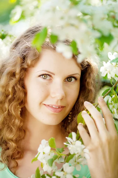 Ung kvinna i blommande trädgård — Stockfoto