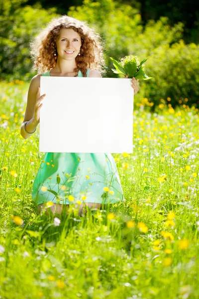 Žena držící bílé prázdné plakát v letním parku — Stock fotografie