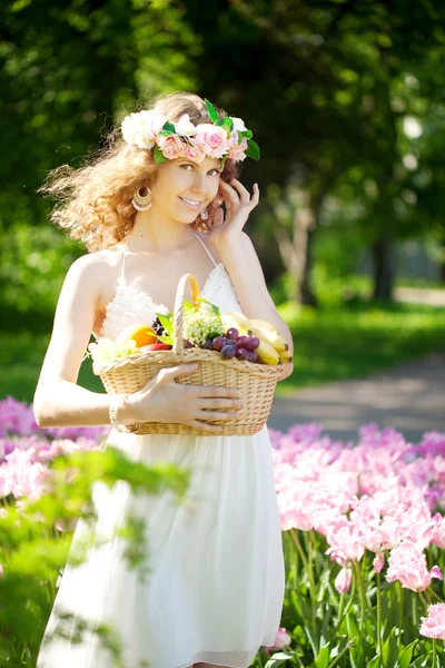 Woman with a basket of fruit in hand — Stock Photo, Image