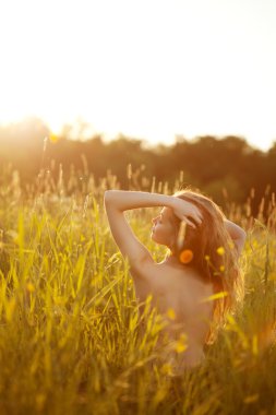 Günbatımında bir alanda gülümseyen güzel kadın