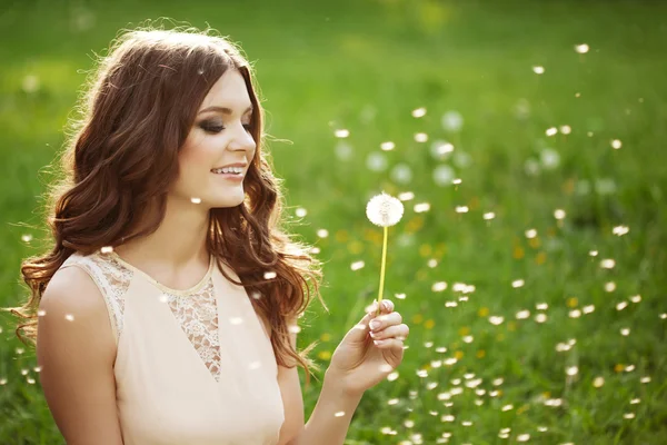 Mooie vrouw waait een paardebloem — Stockfoto