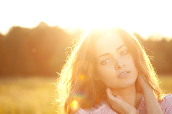Femme souriante dans un champ au coucher du soleil — Photo