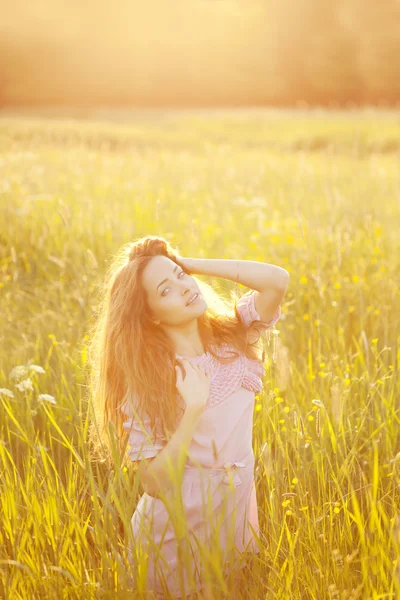 Χαμογελαστή γυναίκα σε ένα χωράφι στο ηλιοβασίλεμα — Φωτογραφία Αρχείου