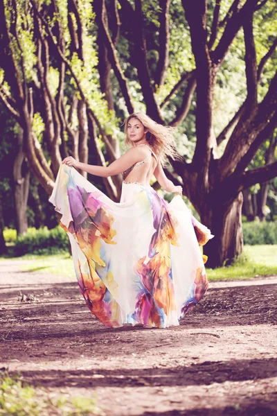 Mujer con un vestido brillante volando en el bosque — Foto de Stock