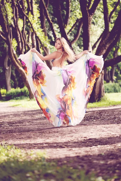 Mujer con un vestido brillante volando en el bosque — Foto de Stock