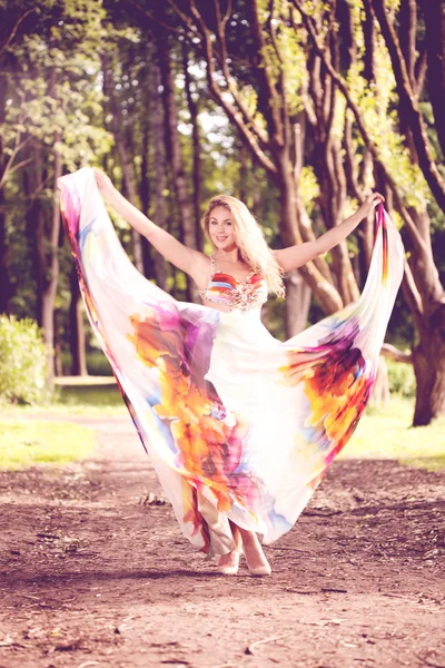 Woman in a bright dress flying in the forest — Stock Photo, Image