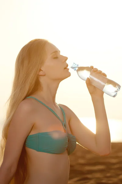 Bella donna con una bottiglia d'acqua sulla spiaggia — Foto Stock