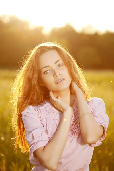 Mulher sorridente em um campo ao pôr do sol Imagens De Bancos De Imagens Sem Royalties