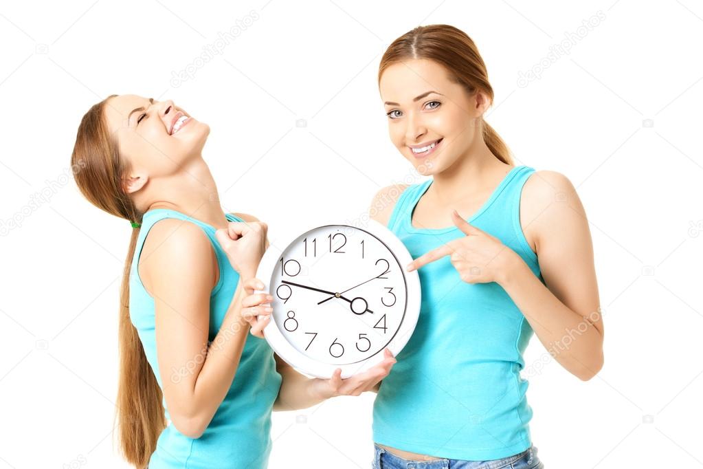 Two smiling women holding a clock