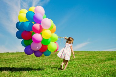 küçük kız holding renkli balonlar. yeşil üzerinde oynayan çocuk