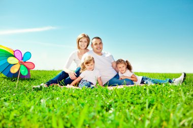 Happy family in outdoor park at sunny day. Mom, dad and two dau clipart