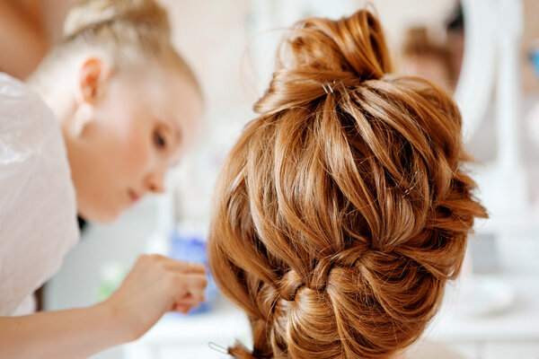 Hair stylist makes the bride before the wedding
