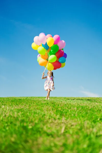 Weinig meisje bedrijf kleurrijke ballonnen. kind spelen op een groen — Stockfoto