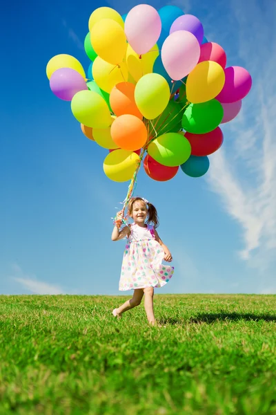 Weinig meisje bedrijf kleurrijke ballonnen. kind spelen op een groen — Stockfoto