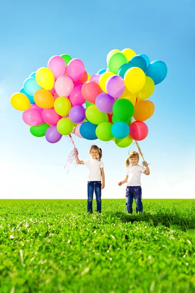 Weinig meisje bedrijf kleurrijke ballonnen. kind spelen op een groen — Stockfoto